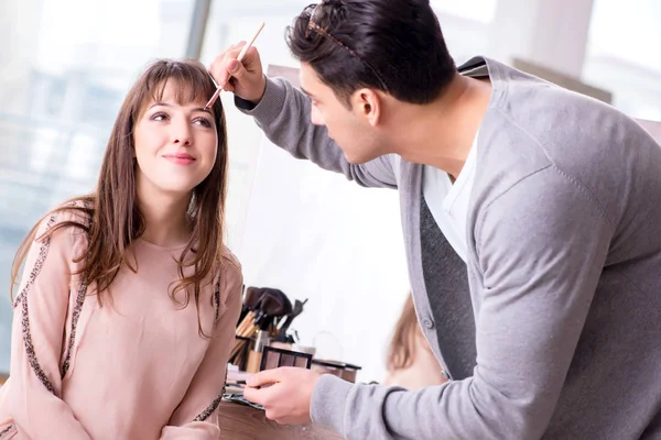 Uomo che fa il make-up per la donna carina nel salone di bellezza — Foto Stock