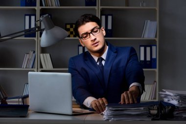 İş adamı fazla mesai ücreti için gece geç saatlere kadar ofiste çalışıyor.