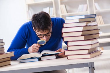 Erkek öğrenci üniversite kütüphanesinde sınava hazırlanıyor.