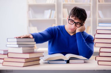 Erkek öğrenci üniversite kütüphanesinde sınava hazırlanıyor.