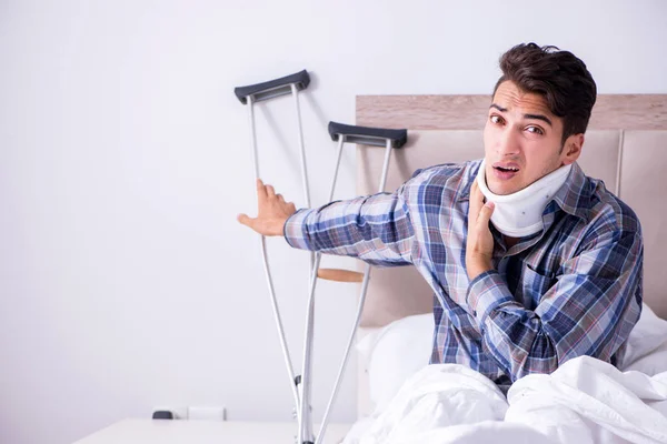 Zraněný muž doma v posteli s berlemi — Stock fotografie