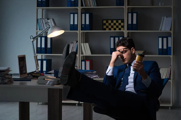 Mitarbeiter arbeitet spät und trinkt starken Kaffee, um wach zu bleiben — Stockfoto