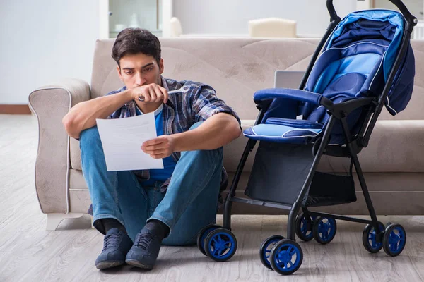 Jovem pai montando carrinho de bebê em casa — Fotografia de Stock