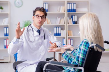 Tekerlekli sandalyedeki engelli kadın erkek doktoru ziyaret ediyor.