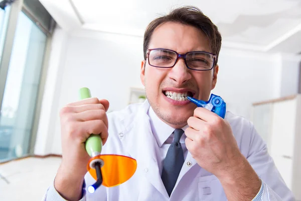 Funny dentist with curing light in medical concept