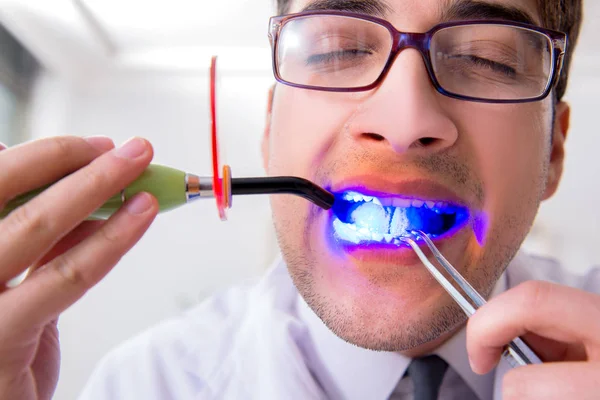 Divertente dentista con la cura della luce nel concetto medico — Foto Stock