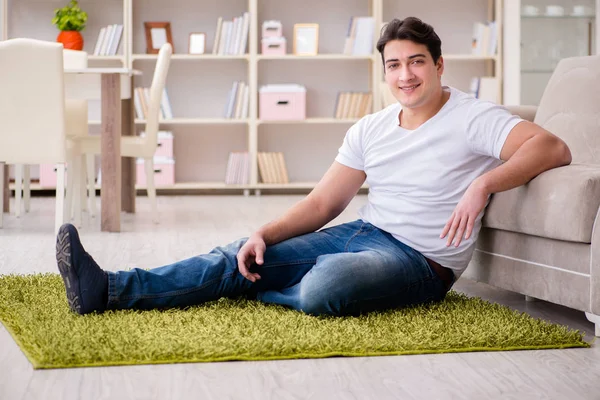 Молодий щасливий красивий чоловік на килимовій підлозі — стокове фото