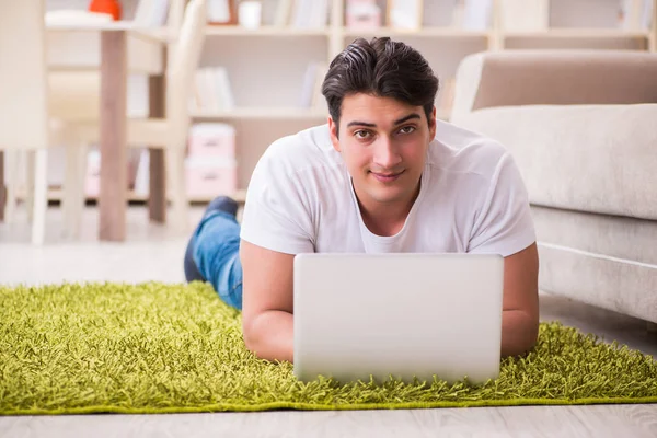 Muž pracující na notebooku doma na podlaze koberce — Stock fotografie