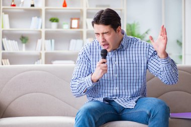 Evde karaoke yapan komik adam.