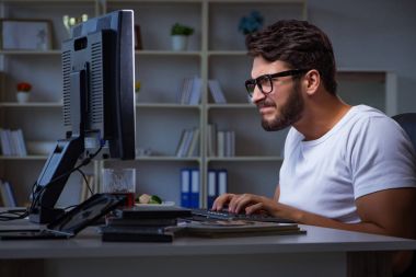 Genç adam fazla mesai yapmak için geç saatlere kadar ofiste kalıyor.