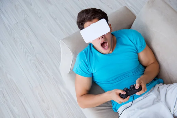 Giovane uomo che indossa occhiali VR rilassante sul divano — Foto Stock
