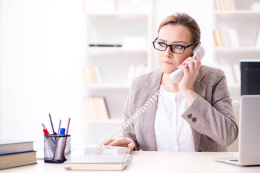 İş kadını çalışan ofis telefonundan konuşuyor.