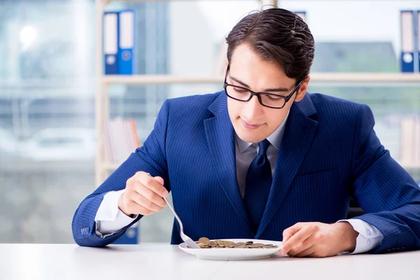 Funny businessman eating gold coins in office