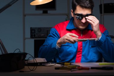 Bilgisayar uzmanı gece geç saatlerde bilgisayarı tamir ediyor.