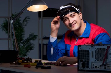 Bilgisayar uzmanı gece geç saatlerde bilgisayarı tamir ediyor.