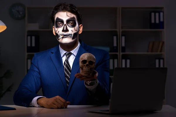 Podnikatel s děsivou obličejovou maskou pracuje pozdě v úřadu — Stock fotografie