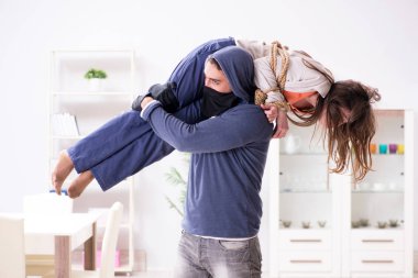 Silahlı bir adam evde genç bir kadına saldırıyor.