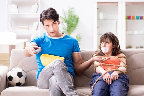 Adam spor maçı izlemek için karısını bağlıyor.