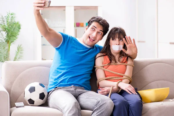 Man bindt zijn vrouw vast om sportvoetbal te kijken — Stockfoto