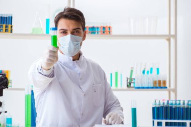 Laboratuvarda kimyasallar üzerinde çalışan genç bir kimyager.