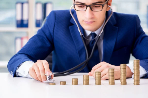 Biznesmen ze stosami monet w biurze — Zdjęcie stockowe