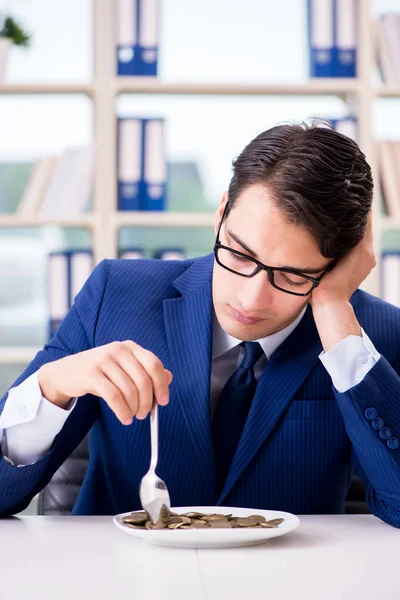 Funny businessman eating gold coins in office