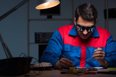 Bilgisayar uzmanı gece geç saatlerde bilgisayarı tamir ediyor.