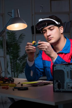 Bilgisayar uzmanı gece geç saatlerde bilgisayarı tamir ediyor.