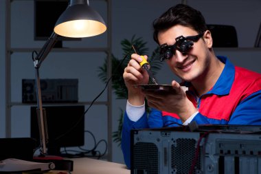 Bilgisayar uzmanı gece geç saatlerde bilgisayarı tamir ediyor.