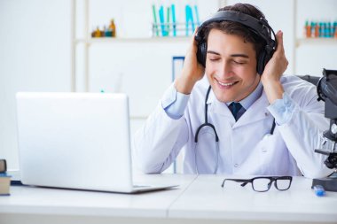 Hastanede öğle arasında müzik dinleyen mutlu doktor.