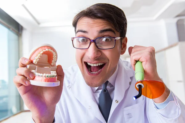 Funny dentist with curing light in medical concept