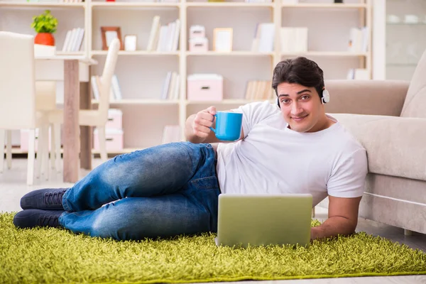 Homem trabalhando no laptop em casa no chão do tapete — Fotografia de Stock