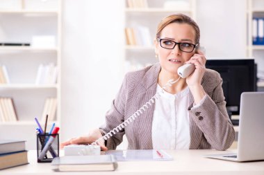 İş kadını çalışan ofis telefonundan konuşuyor.