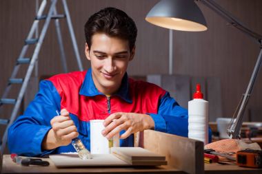 Genç adam ahşap parçaları DIY konseptinde yapıştırıyor.