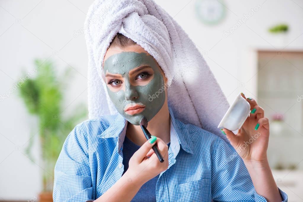 Woman applying clay mask with brush at home