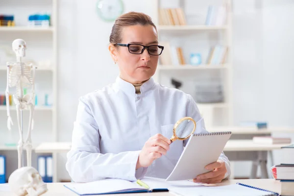 Kvinna läkare studerar mänskligt skelett — Stockfoto