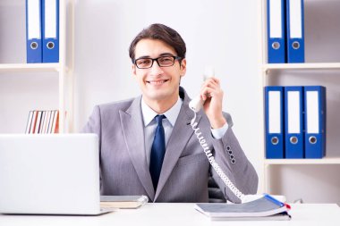 İşadamı ofis telefonundan konuşuyor.