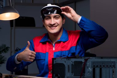 Bilgisayar uzmanı gece geç saatlerde bilgisayarı tamir ediyor.