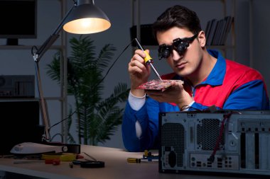 Bilgisayar uzmanı gece geç saatlerde bilgisayarı tamir ediyor.