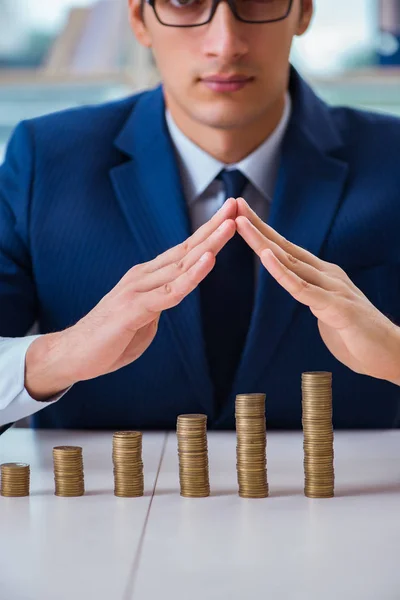 Empresario con pilas de monedas en la oficina —  Fotos de Stock