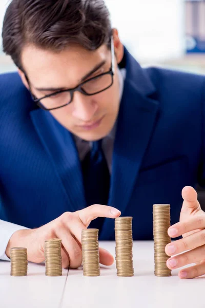 Geschäftsmann mit Stapeln von Münzen im Büro — Stockfoto