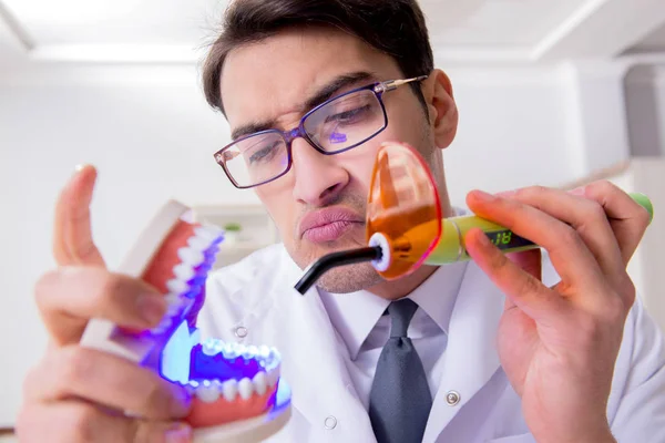 Funny dentist with curing light in medical concept