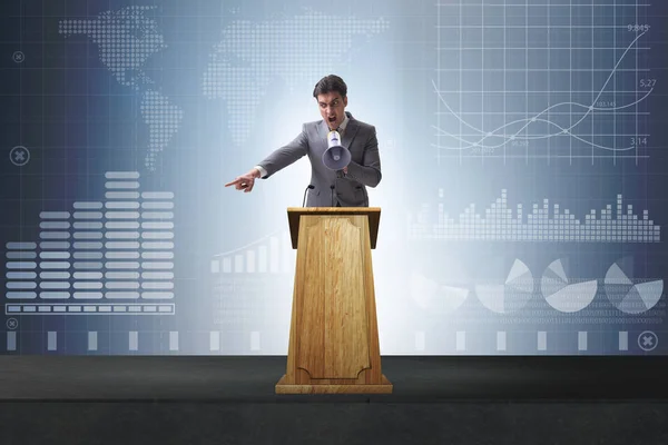 Hombre de negocios haciendo discurso en la tribuna en el concepto de negocio — Foto de Stock