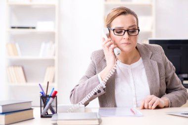 İş kadını çalışan ofis telefonundan konuşuyor.
