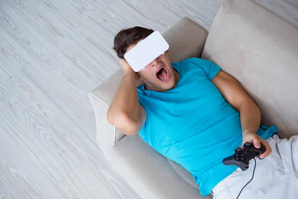 Hombre joven con gafas VR relajándose en sofá —  Fotos de Stock