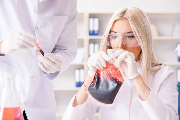 Mulher médica olhando para amostras de sangue no saco — Fotografia de Stock