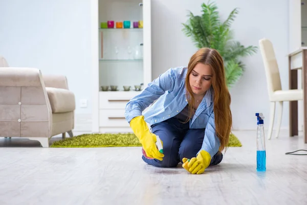 Νεαρή γυναίκα που καθαρίζει το πάτωμα στο σπίτι κάνοντας δουλειές — Φωτογραφία Αρχείου