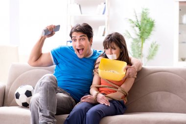 Adam spor maçı izlemek için karısını bağlıyor.