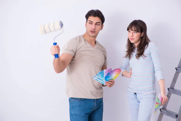 Jovem família fazendo renovação em casa - paredes de pintura — Fotografia de Stock