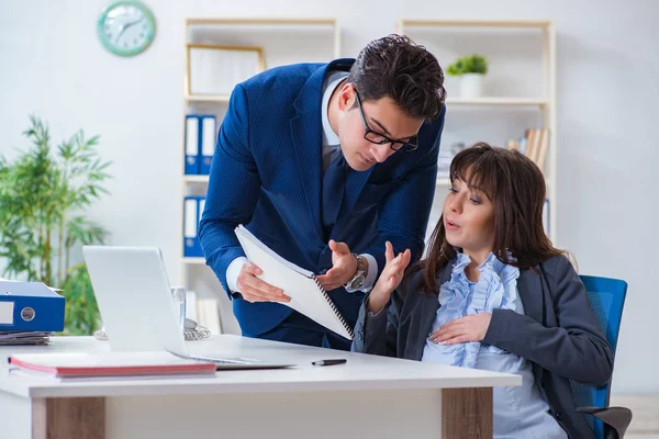 Pregnant woman struggling in the office and getting colleague he